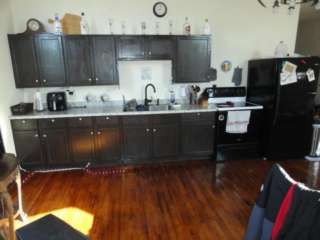 kitchen featuring electric range, a sink, dark wood finished floors, freestanding refrigerator, and light countertops