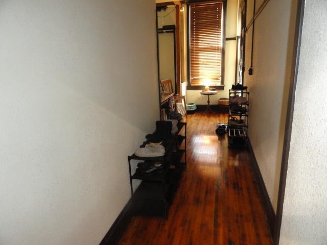 corridor with baseboards and wood finished floors