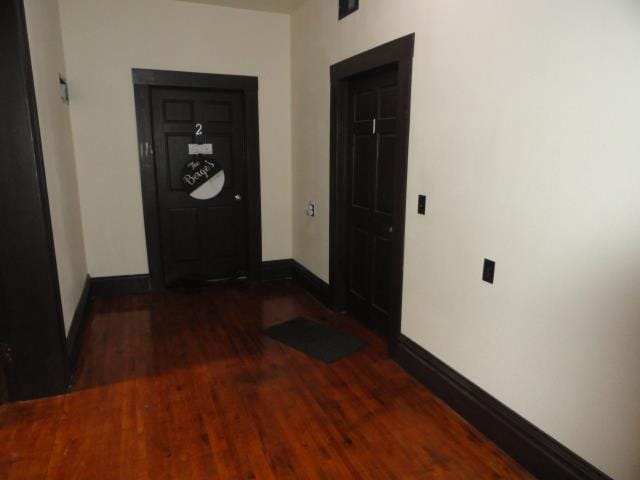 hall with baseboards and wood finished floors