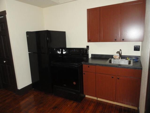 kitchen with black appliances, dark countertops, dark wood-type flooring, and a sink