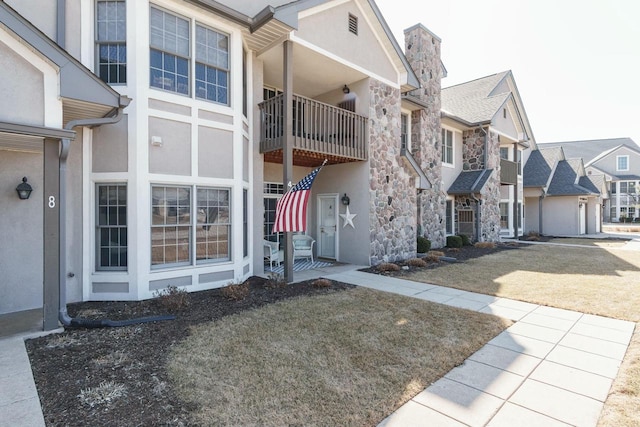 exterior space with stucco siding, stone siding, a residential view, and a chimney