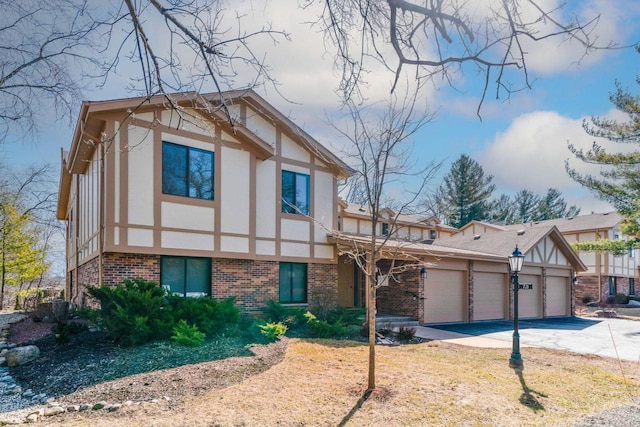 tudor home featuring stucco siding, brick siding, and an attached garage