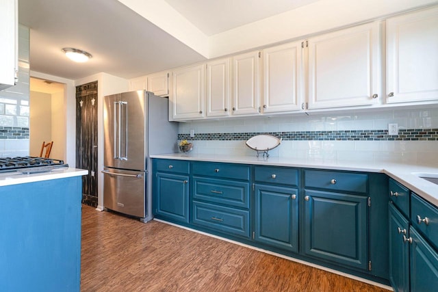 kitchen featuring dark wood-style floors, appliances with stainless steel finishes, white cabinetry, blue cabinets, and backsplash