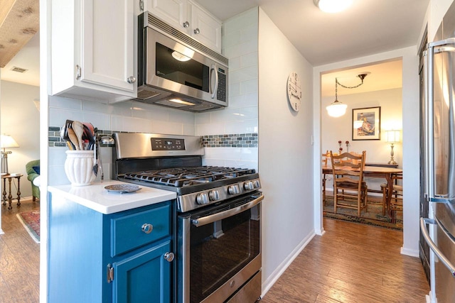 kitchen with blue cabinetry, tasteful backsplash, wood finished floors, stainless steel appliances, and white cabinets