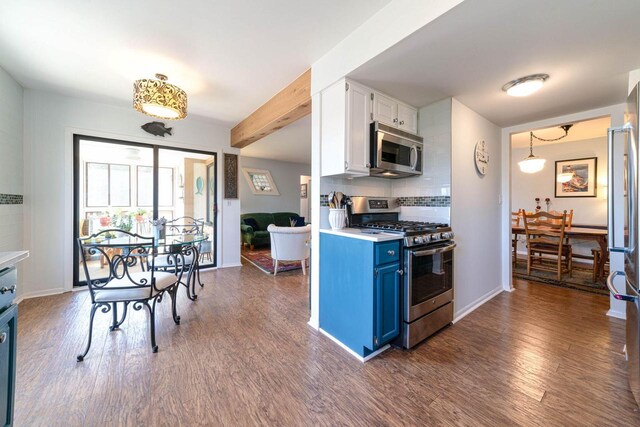 kitchen featuring dark wood-style floors, blue cabinetry, stainless steel appliances, decorative backsplash, and white cabinets