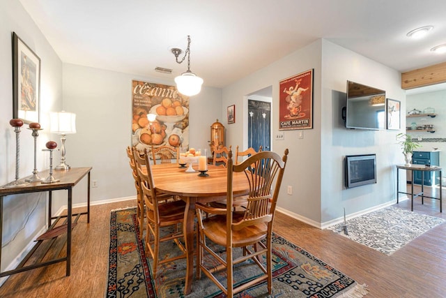 dining area with a fireplace, wood finished floors, and baseboards