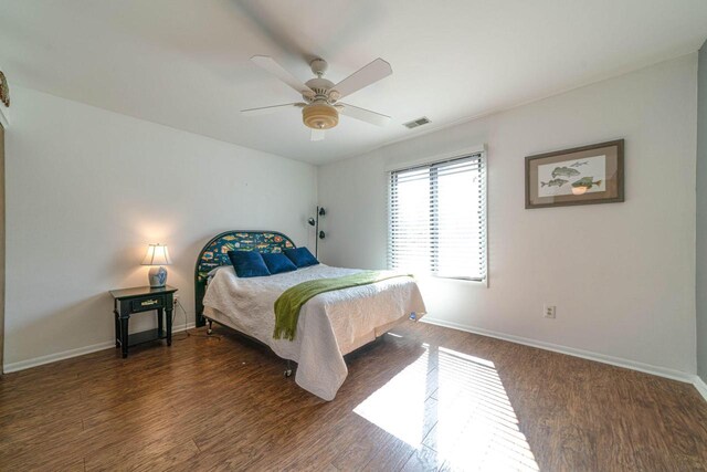 bedroom with visible vents, a ceiling fan, baseboards, and wood finished floors