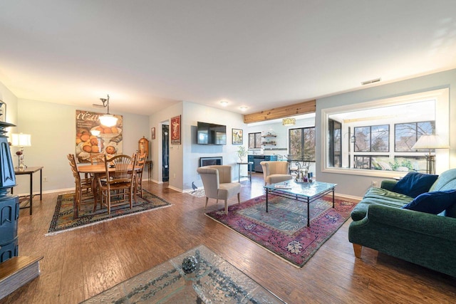 living room featuring visible vents, baseboards, a fireplace, and hardwood / wood-style flooring