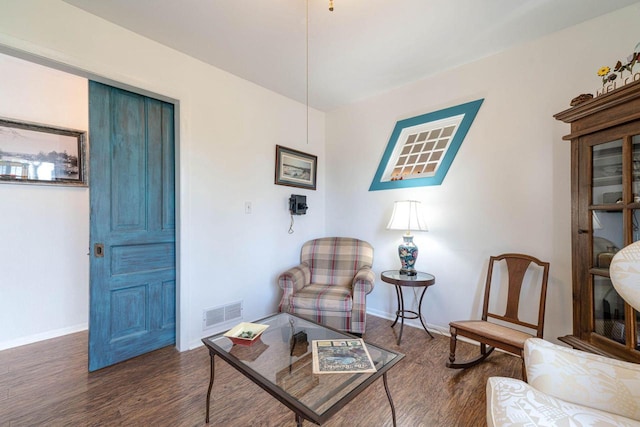 living area with wood finished floors, visible vents, and baseboards