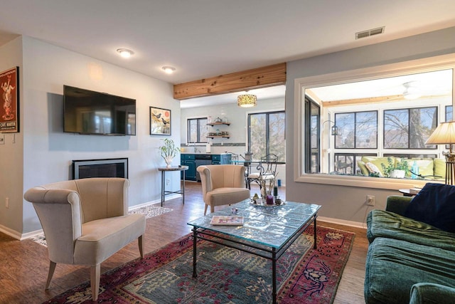 living area featuring visible vents, baseboards, wood finished floors, and a fireplace