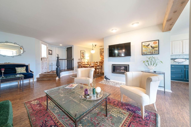 living area with a glass covered fireplace, baseboards, and wood finished floors