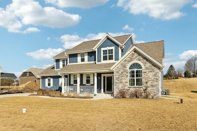 view of front of property featuring a front lawn, a porch, central AC, roof with shingles, and stone siding