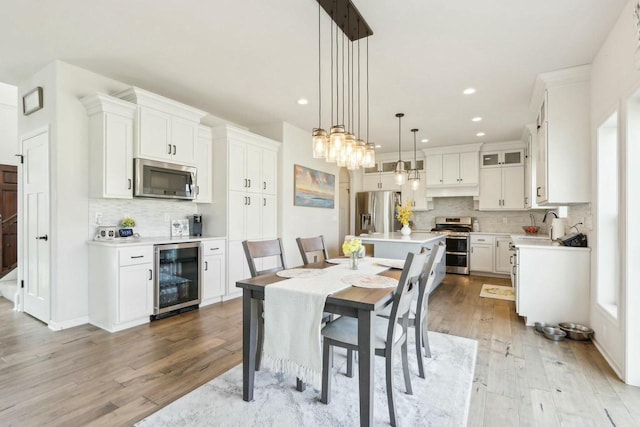 dining area featuring recessed lighting, light wood-style floors, and beverage cooler