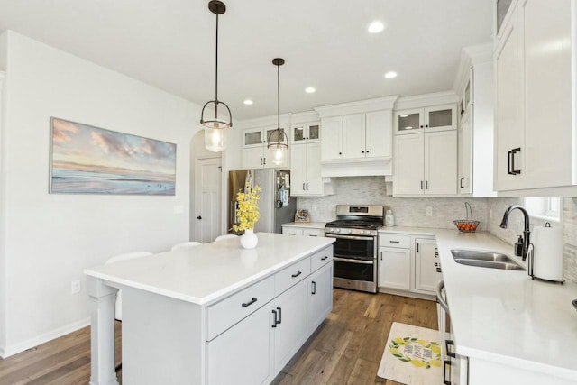 kitchen featuring a sink, custom range hood, appliances with stainless steel finishes, tasteful backsplash, and a center island