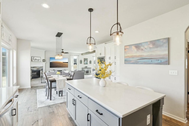 kitchen featuring a stone fireplace, light wood-style flooring, pendant lighting, and a center island