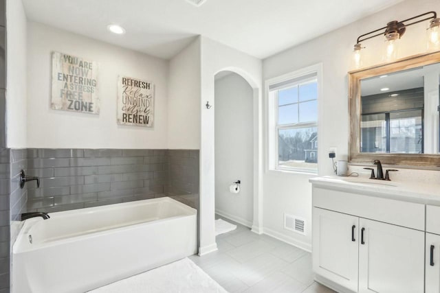 full bath featuring visible vents, recessed lighting, baseboards, a bath, and vanity