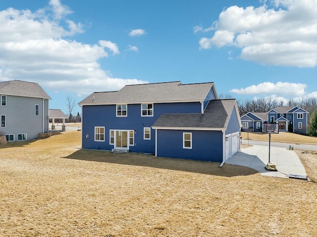 back of house featuring a garage, a residential view, roof with shingles, and concrete driveway