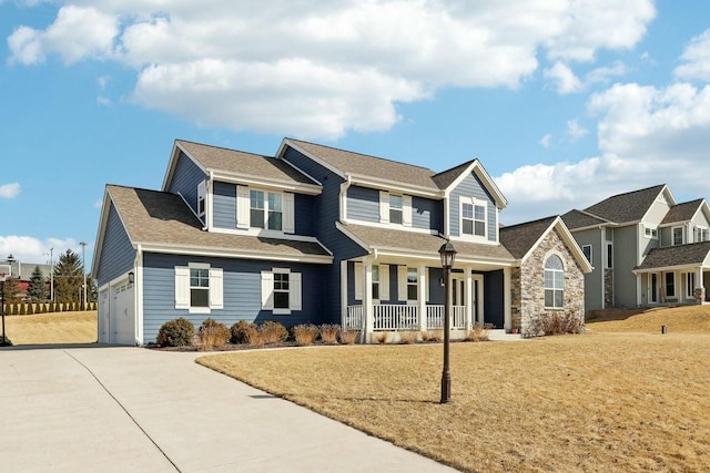 view of front facade with a shingled roof, a front lawn, covered porch, stone siding, and driveway