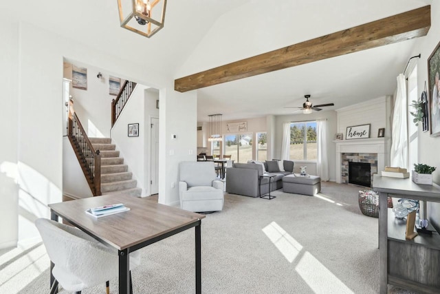 carpeted living area with ceiling fan, stairway, beam ceiling, a stone fireplace, and high vaulted ceiling