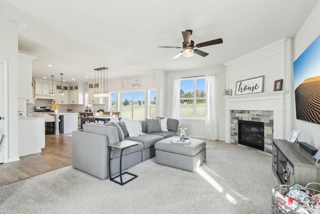 living room featuring a glass covered fireplace, light wood-style flooring, ceiling fan, and recessed lighting