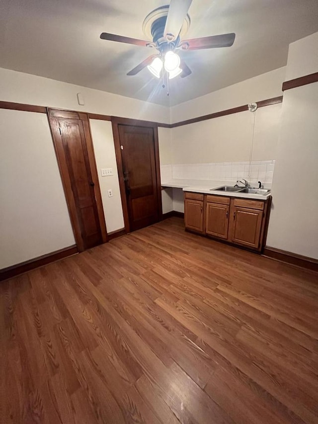 kitchen with wood finished floors, light countertops, a ceiling fan, and a sink