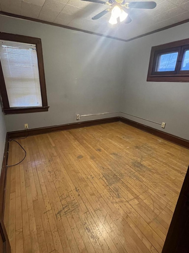 empty room with baseboards, wood-type flooring, and ceiling fan