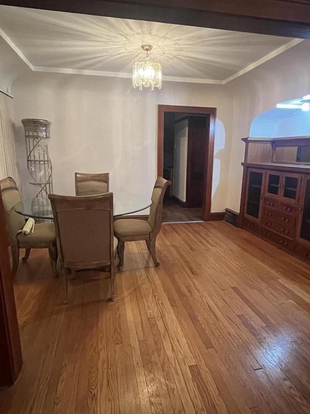 dining room featuring crown molding, an inviting chandelier, and wood finished floors