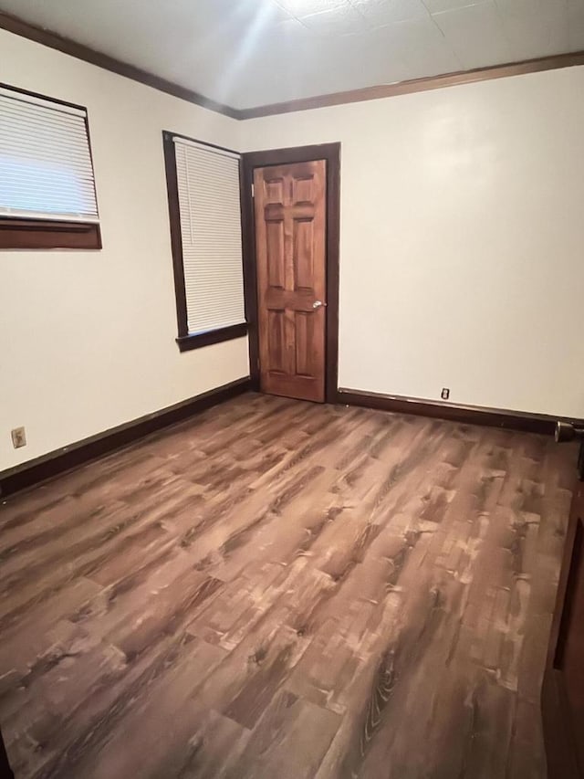 spare room with ornamental molding, baseboards, and wood finished floors