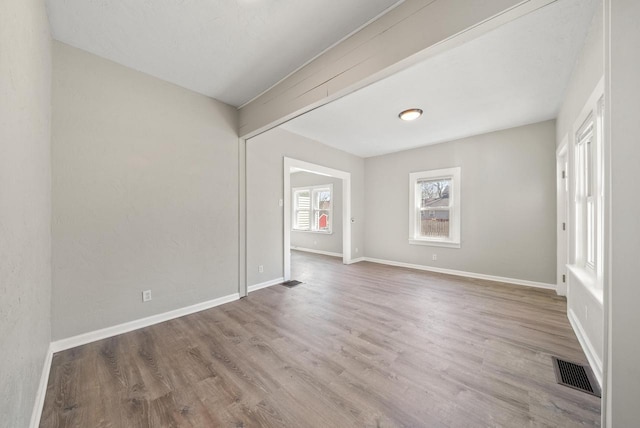 empty room featuring visible vents, baseboards, and wood finished floors