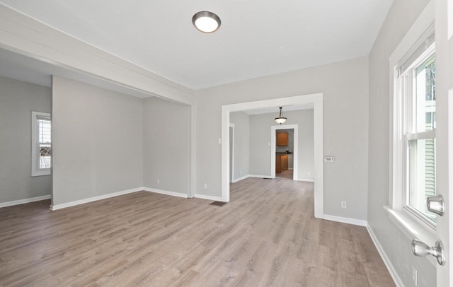 spare room featuring baseboards and light wood-style floors