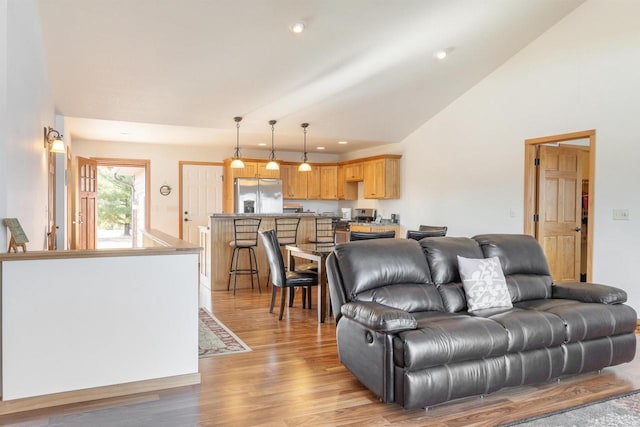 living area with recessed lighting, light wood-type flooring, and high vaulted ceiling