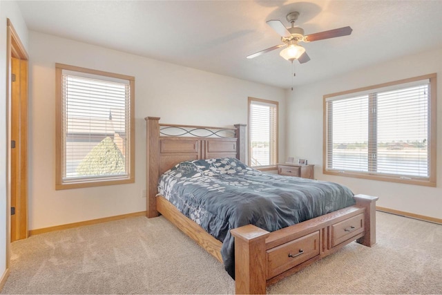 bedroom with light carpet, a ceiling fan, and baseboards