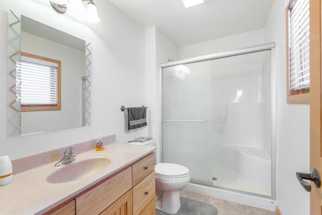 bathroom featuring tile patterned flooring, a shower stall, toilet, and vanity