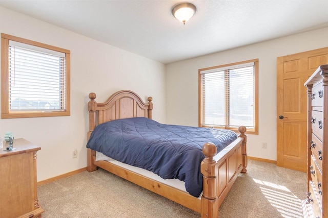 bedroom with baseboards, multiple windows, and light carpet