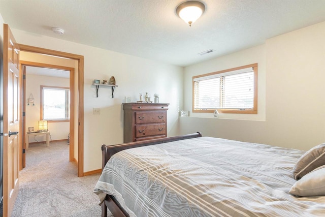 bedroom featuring visible vents, carpet floors, a textured ceiling, and baseboards