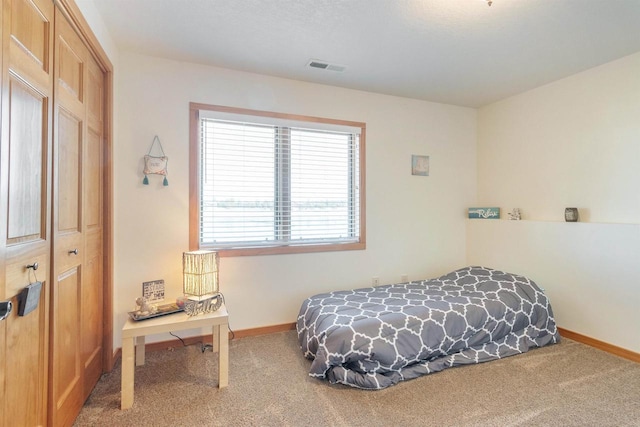 carpeted bedroom with a closet, visible vents, and baseboards