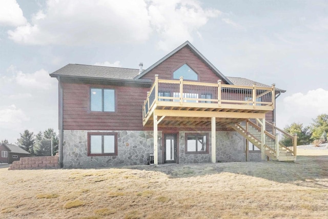 rear view of property featuring a deck, stairway, a yard, and stone siding