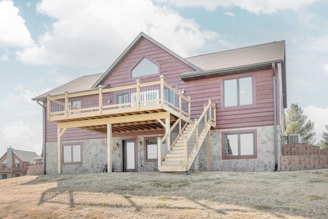 rear view of property featuring a yard, stone siding, a deck, and stairs