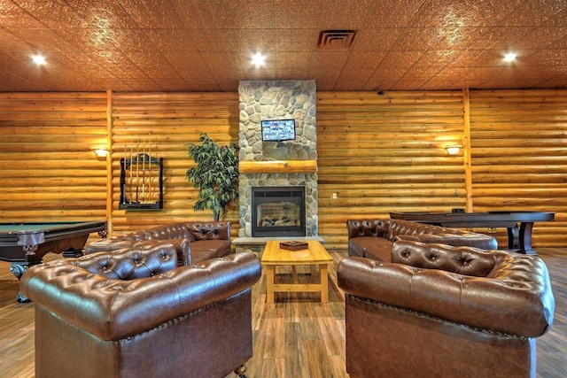 living area with visible vents, wood finished floors, a stone fireplace, pool table, and log walls