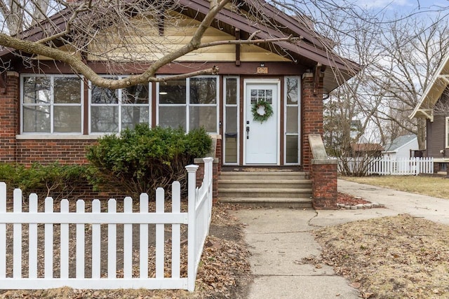 entrance to property featuring fence and brick siding