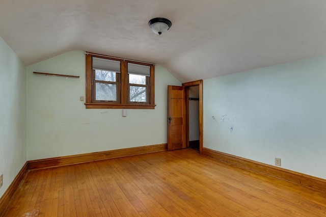 additional living space featuring light wood-type flooring, baseboards, and vaulted ceiling