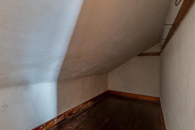 bonus room with lofted ceiling, dark wood-style floors, and baseboards