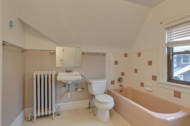 full bathroom featuring a wainscoted wall, toilet, radiator heating unit, lofted ceiling, and a tub to relax in