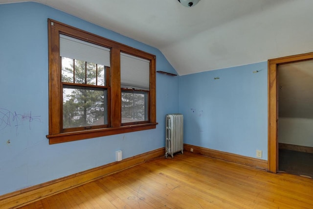 additional living space with hardwood / wood-style flooring, radiator, baseboards, and vaulted ceiling