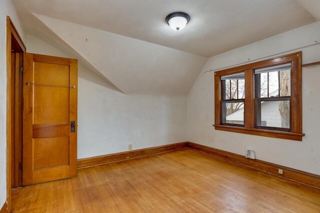 bonus room featuring lofted ceiling, light wood-style floors, and baseboards