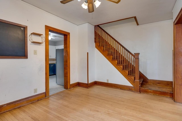 unfurnished living room with baseboards, ornamental molding, stairs, hardwood / wood-style flooring, and ceiling fan