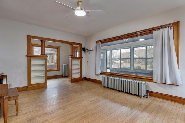 unfurnished room with light wood-style flooring, radiator, a ceiling fan, and baseboards