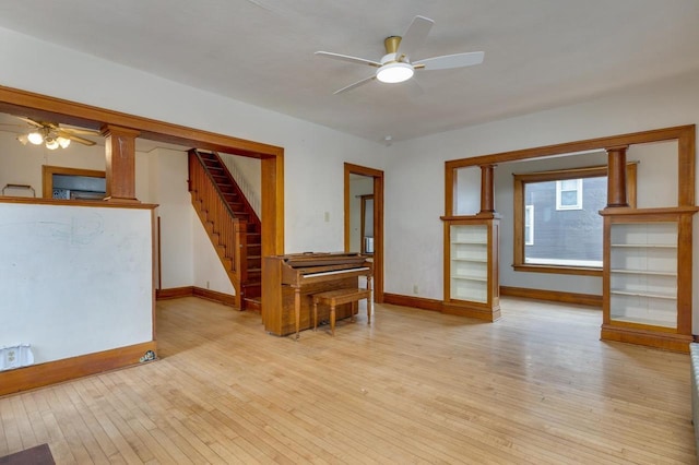 unfurnished living room with stairs, light wood-type flooring, baseboards, and a ceiling fan