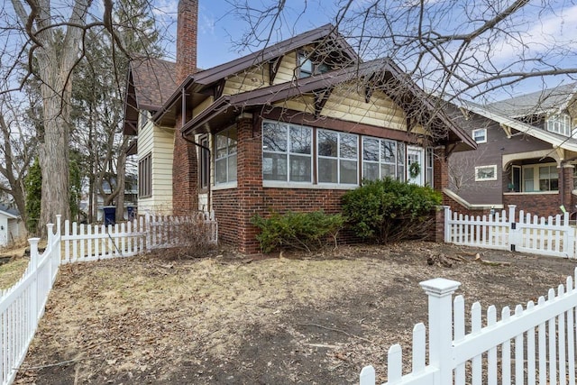 bungalow-style home with a fenced front yard and brick siding