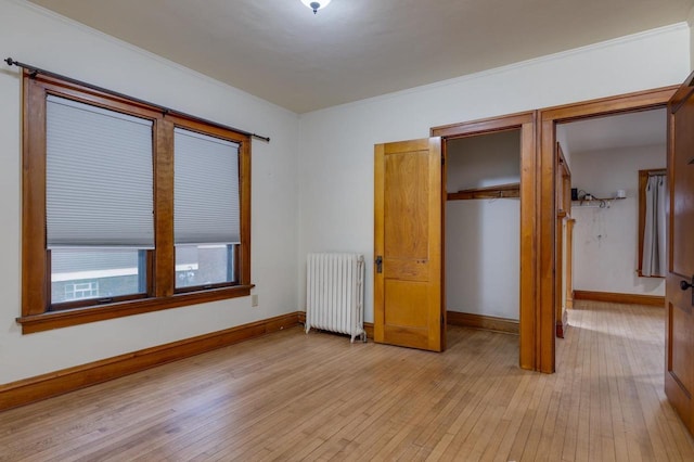 unfurnished bedroom featuring a closet, light wood-type flooring, radiator heating unit, and baseboards